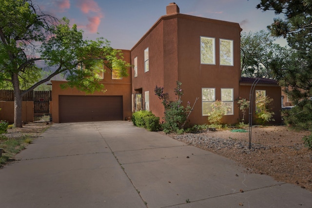 view of side of home with stucco siding, a chimney, concrete driveway, and fence