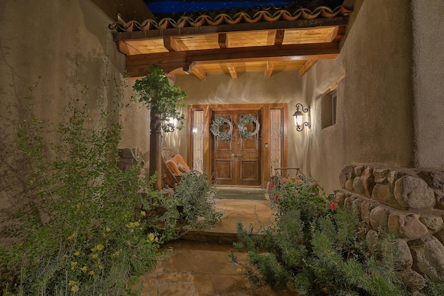 doorway to property featuring a tiled roof and stucco siding