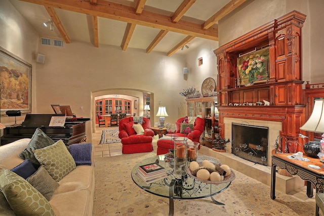 living room featuring a high ceiling, visible vents, arched walkways, beam ceiling, and a fireplace