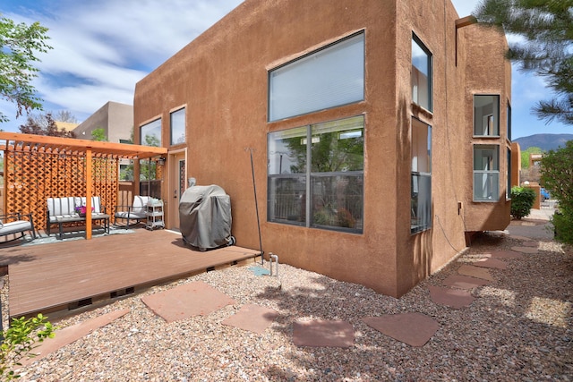 back of property with stucco siding, a deck, and an outdoor living space