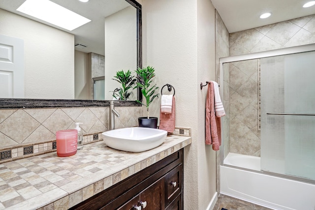 full bathroom featuring recessed lighting, a skylight, shower / bath combination with glass door, backsplash, and vanity