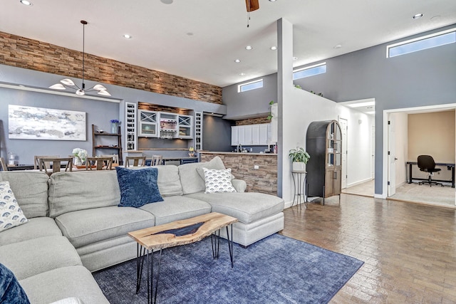 living room with recessed lighting, ceiling fan, brick floor, and a towering ceiling