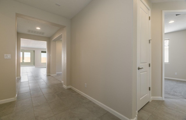 hall featuring light tile patterned flooring, baseboards, and visible vents