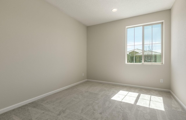 carpeted spare room with baseboards and a textured ceiling
