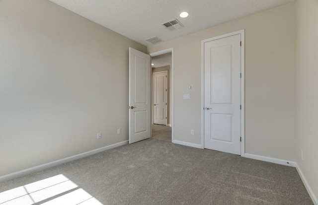 unfurnished bedroom with carpet floors, baseboards, and visible vents