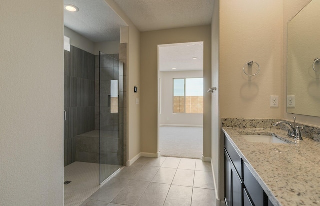 full bathroom featuring baseboards, tiled shower, vanity, and a textured ceiling