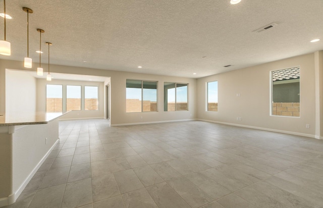 tiled spare room with a textured ceiling, plenty of natural light, baseboards, and recessed lighting