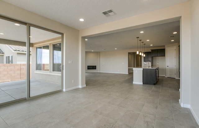unfurnished living room with a sink, light tile patterned flooring, visible vents, recessed lighting, and baseboards