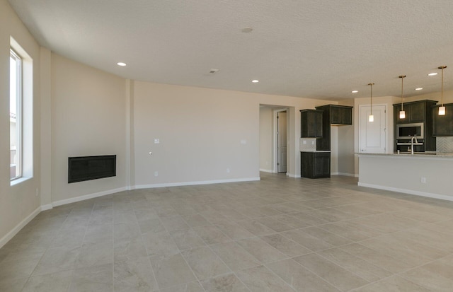 unfurnished living room with a textured ceiling, a glass covered fireplace, and recessed lighting