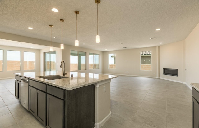 kitchen featuring dishwasher, a textured ceiling, baseboards, and a sink