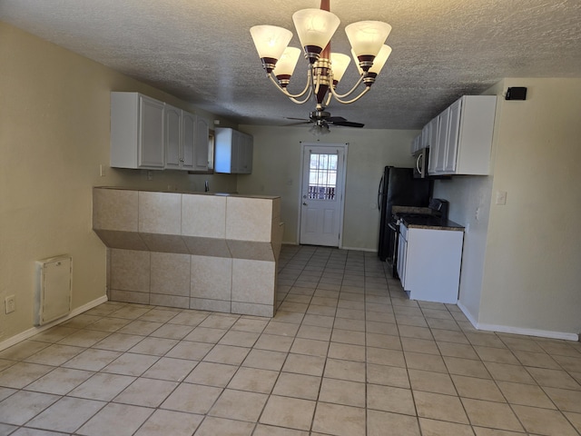 kitchen featuring stove, light tile patterned floors, baseboards, a textured ceiling, and white cabinetry