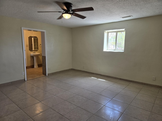 spare room with a ceiling fan, tile patterned flooring, a textured ceiling, and visible vents