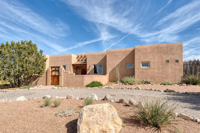 adobe home with fence, a gate, and stucco siding