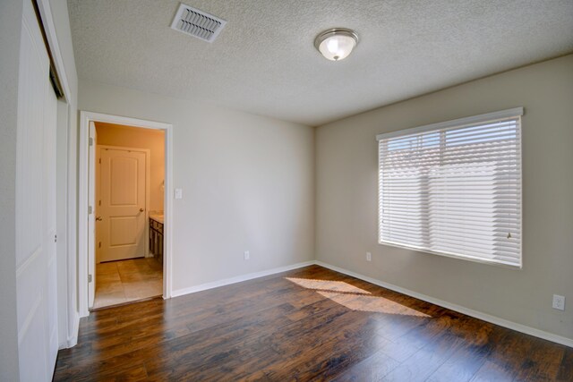 7227 Wasilla Dr NE, Rio Rancho, NM 87144 - empty room featuring a textured ceiling, visible vents, baseboards, and dark wood-style flooring