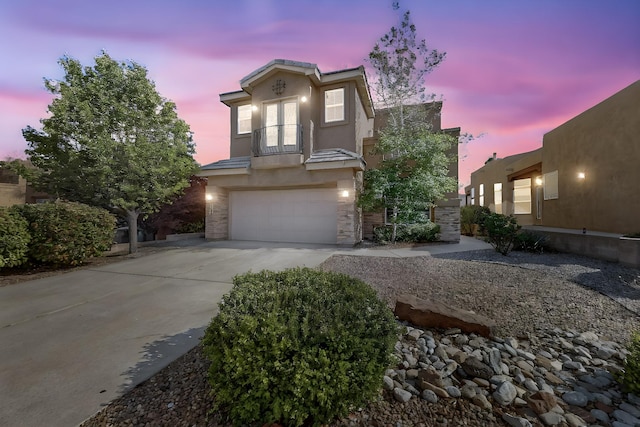 3404 Lockerbie Dr SE, Rio Rancho, NM 87124 - view of front facade featuring driveway, stone siding, an attached garage, a balcony, and stucco siding