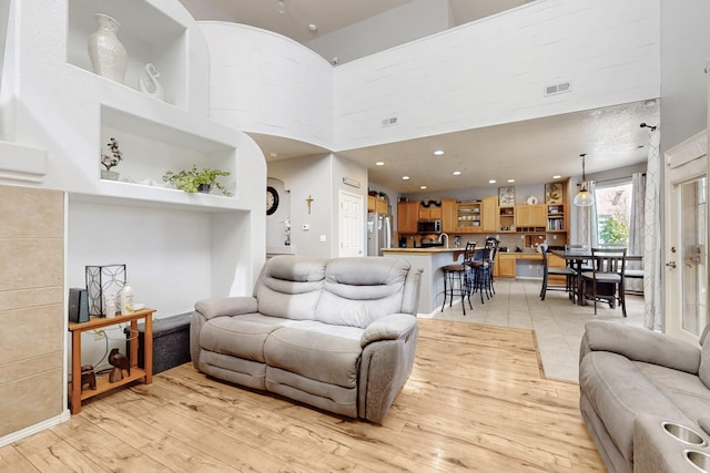 3404 Lockerbie Dr SE, Rio Rancho, NM 87124 - living room featuring a towering ceiling, light wood-style flooring, visible vents, and recessed lighting