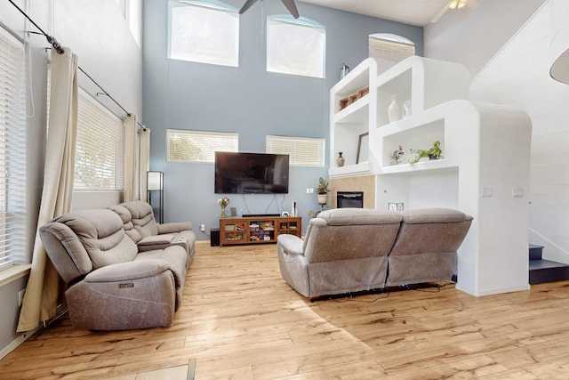 3404 Lockerbie Dr SE, Rio Rancho, NM 87124 - living room with a tiled fireplace, baseboards, a towering ceiling, wood finished floors, and ceiling fan