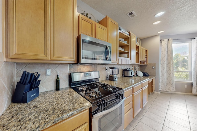 3404 Lockerbie Dr SE, Rio Rancho, NM 87124 - kitchen featuring light stone counters, stainless steel appliances, backsplash, visible vents, and a textured ceiling