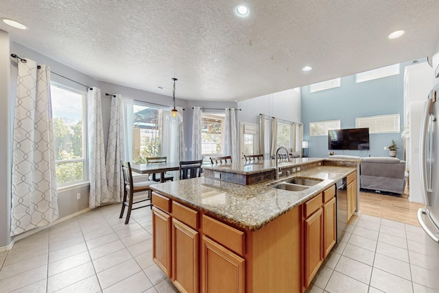 3404 Lockerbie Dr SE, Rio Rancho, NM 87124 - kitchen with stainless steel dishwasher, a textured ceiling, a sink, brown cabinets, and an island with sink