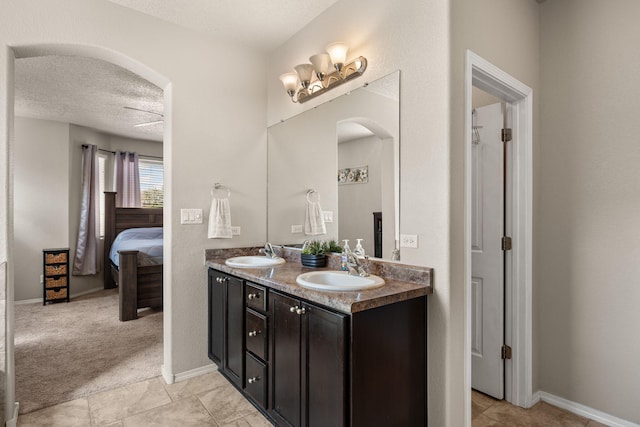 ensuite bathroom featuring double vanity, a textured ceiling, ensuite bath, and a sink