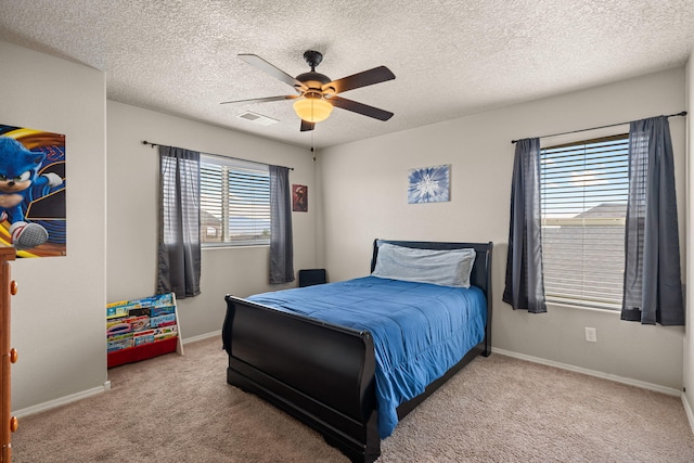 carpeted bedroom with a textured ceiling, visible vents, a ceiling fan, and baseboards
