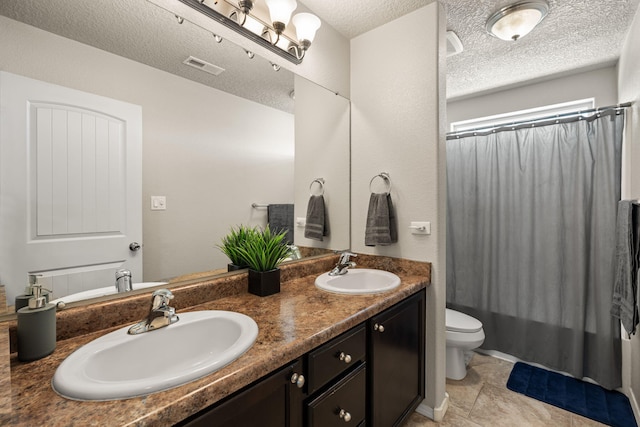 bathroom featuring visible vents, toilet, double vanity, and a sink