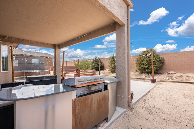 view of patio featuring a bar, a trampoline, and a fenced backyard