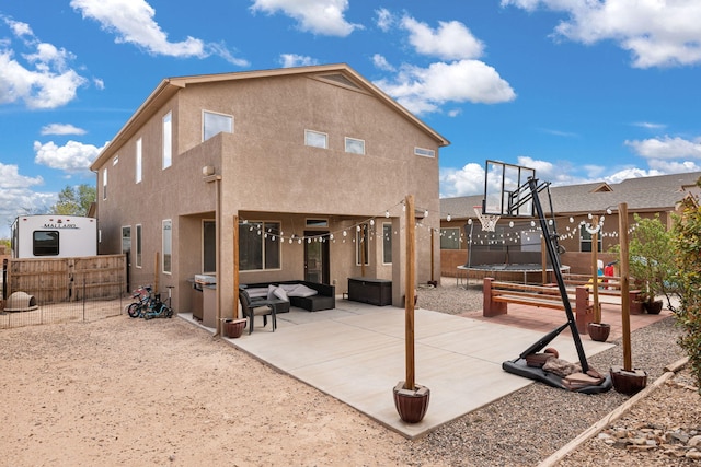 back of property featuring a trampoline, a patio area, stucco siding, an outdoor living space, and a fenced backyard