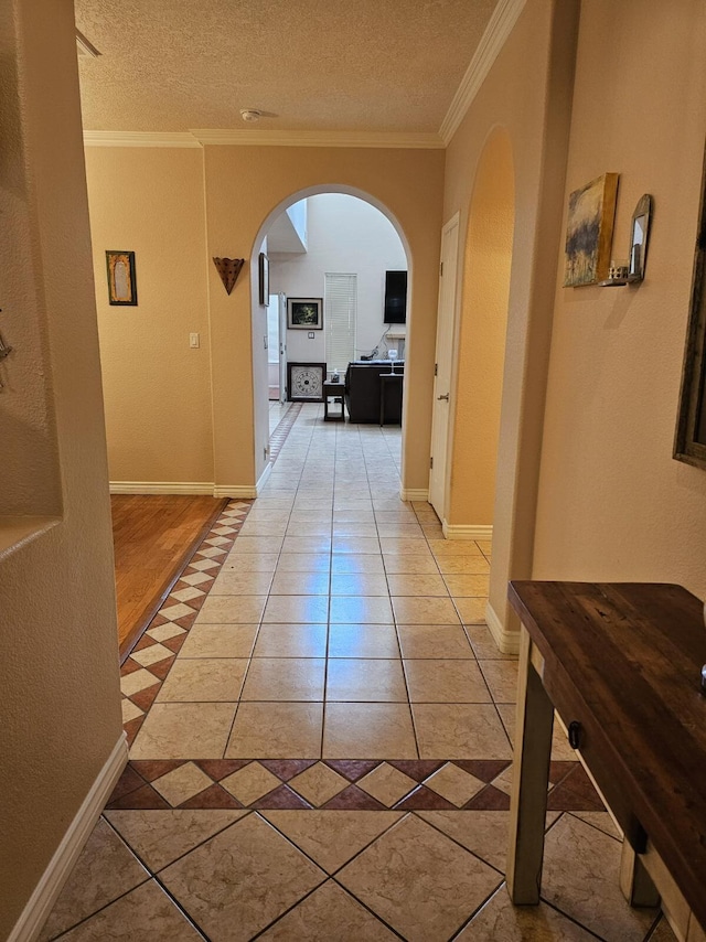 hall with arched walkways, a textured ceiling, crown molding, and light tile patterned flooring