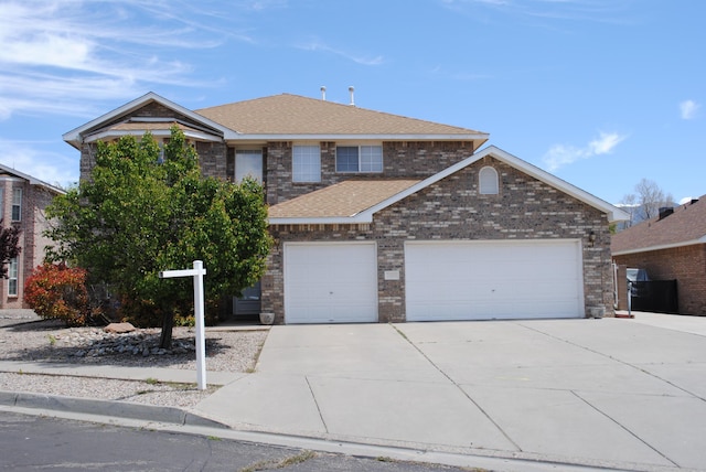 traditional-style house with a garage, roof with shingles, brick siding, and concrete driveway