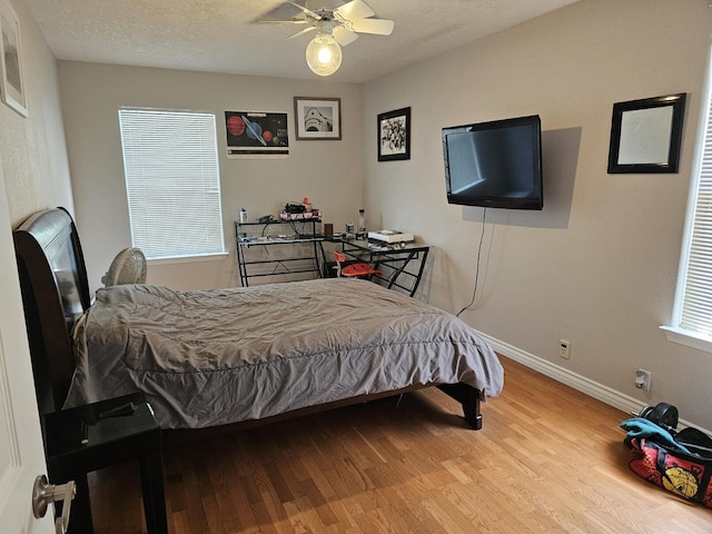 bedroom featuring wood finished floors, baseboards, and multiple windows