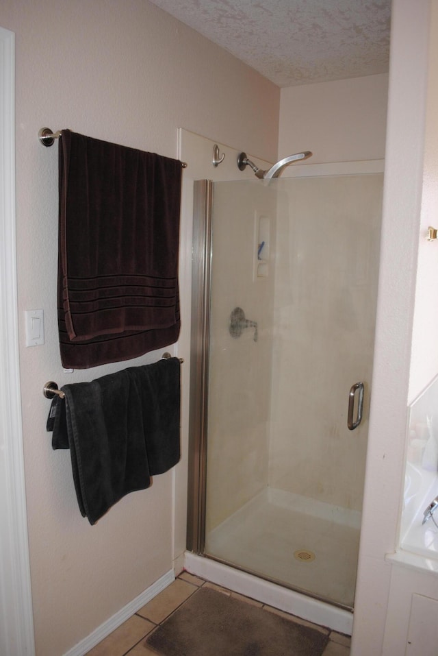 bathroom featuring a shower stall, tile patterned floors, and a textured ceiling