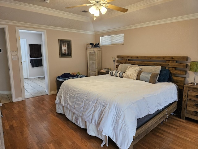 bedroom with ceiling fan, wood finished floors, baseboards, and ornamental molding