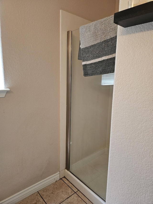full bath featuring a shower stall, tile patterned flooring, and baseboards