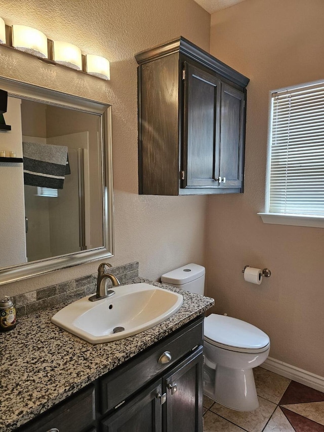 bathroom with tile patterned flooring, toilet, vanity, and baseboards