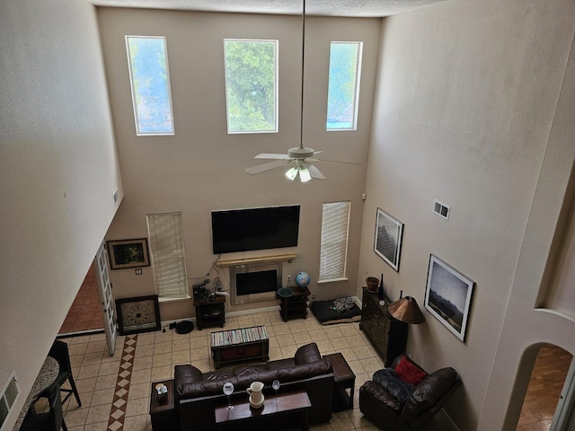 living area with visible vents, a towering ceiling, a ceiling fan, and light tile patterned floors
