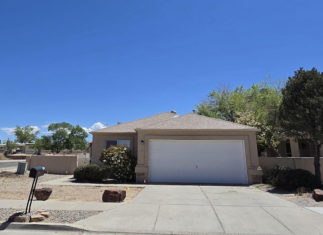 ranch-style home featuring driveway, a shingled roof, an attached garage, and fence