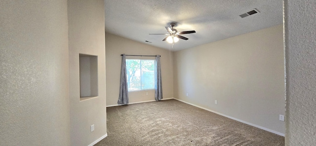 spare room with visible vents, dark colored carpet, a ceiling fan, and a textured wall