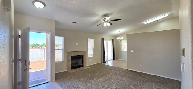 unfurnished living room featuring a fireplace, light tile patterned flooring, visible vents, vaulted ceiling, and ceiling fan with notable chandelier