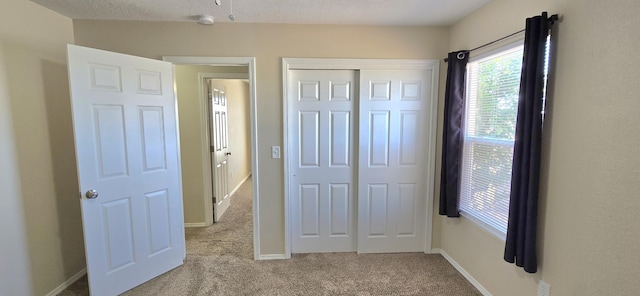unfurnished bedroom featuring baseboards, carpet floors, and a closet