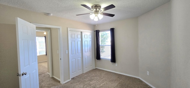 unfurnished bedroom with a closet, a ceiling fan, carpet, baseboards, and a textured ceiling