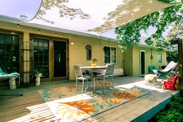 rear view of house with a deck, french doors, outdoor dining space, and stucco siding