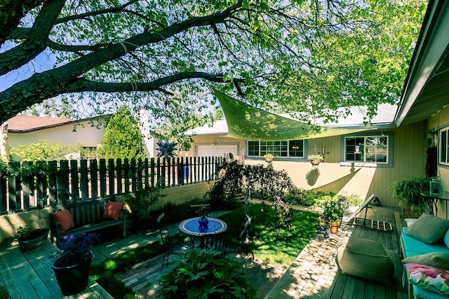 exterior space featuring an attached garage, fence, and a deck