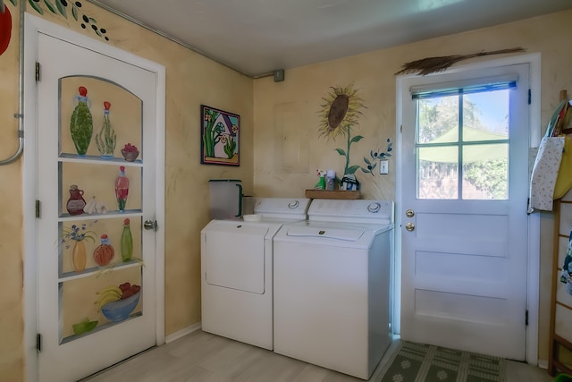 clothes washing area with light wood-style floors, separate washer and dryer, and laundry area