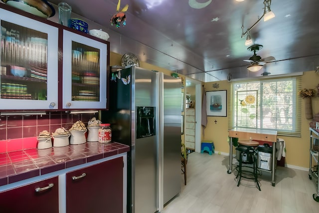 kitchen with tasteful backsplash, baseboards, a ceiling fan, stainless steel refrigerator with ice dispenser, and tile countertops