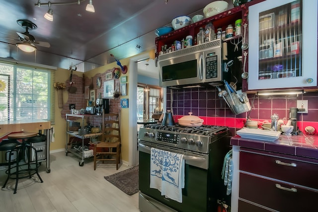 kitchen featuring tile counters, backsplash, a ceiling fan, and stainless steel appliances