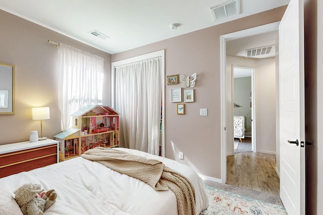 bedroom featuring baseboards, wood finished floors, and visible vents