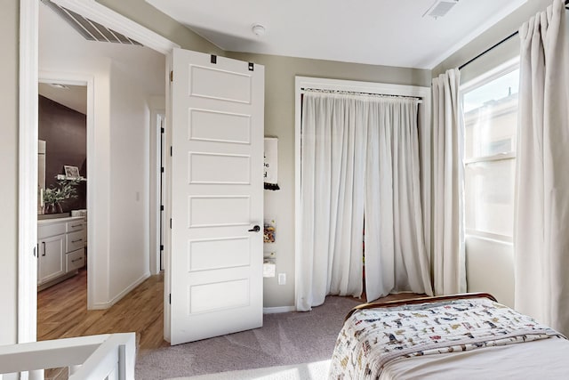 bedroom with baseboards, visible vents, and light colored carpet