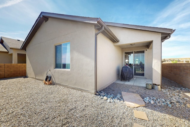 back of property with a fenced backyard, a patio, and stucco siding