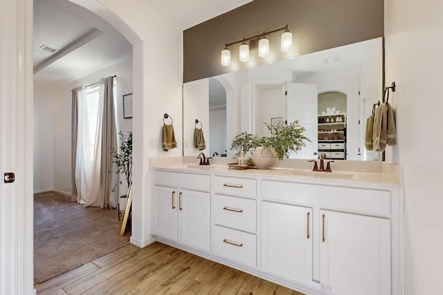 full bathroom featuring visible vents, wood finished floors, a sink, and double vanity